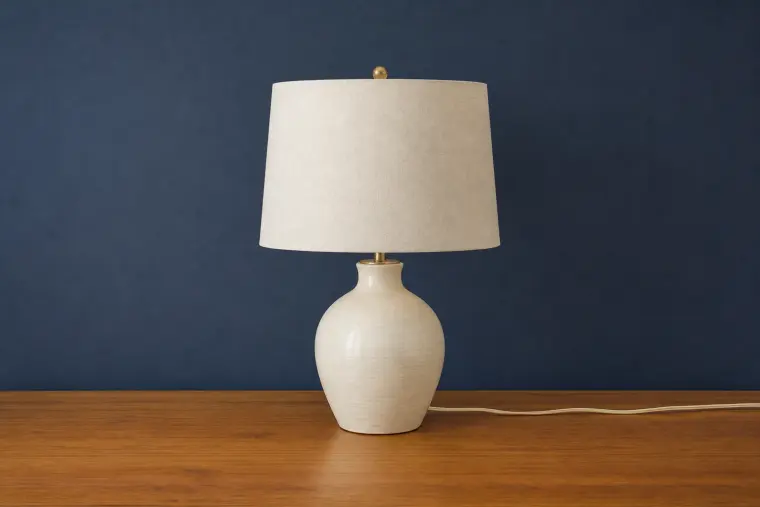 Cream ceramic table lamp photographed with clear edges and a contrasting navy background as a strong source-image example.